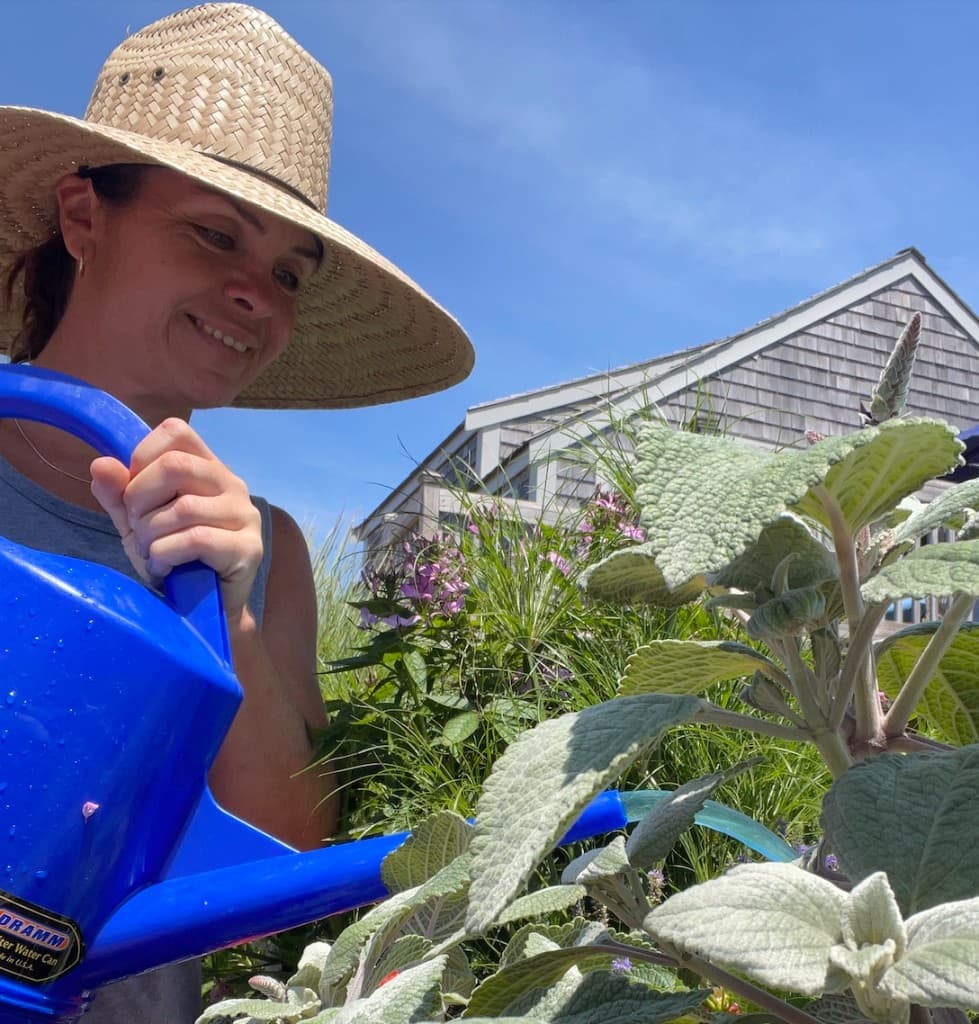 Andrea watering plants in a Nantucket garden